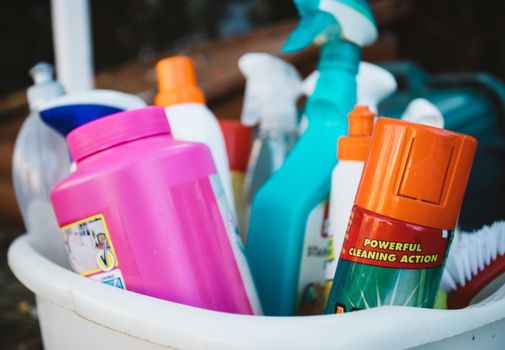 commercial-plumbing Close-up of assorted cleaning supplies in a bucket outdoors, showcasing various detergents and sprays.